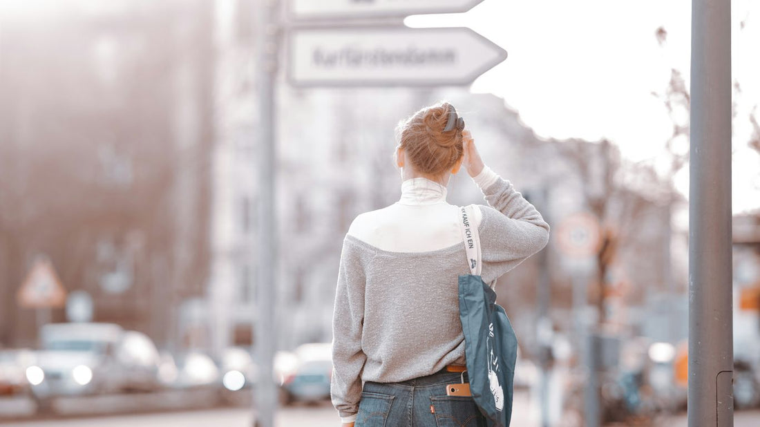woman in white long sleeve shirt and blue denim jeans standing on sidewalk during daytime