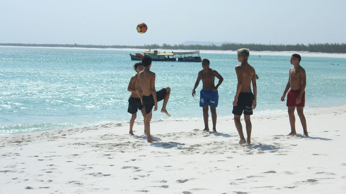 Boys playing soccer on a sunny beach