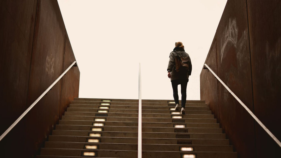 man in black jacket walking on brown wooden staircase